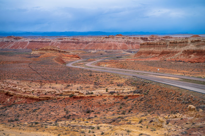 Highway cutting through the desert with flats and colorful canyons.