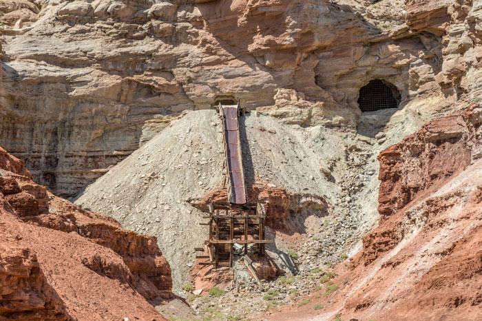 Abandoned uranium mine in a Utah canyon with rusted equipment.