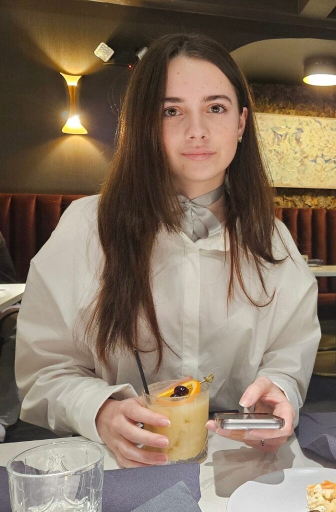 Picture of a Discover All Corners child 2 - a young girl dressed elegantly, sitting at a dining table in a fancy restaurant