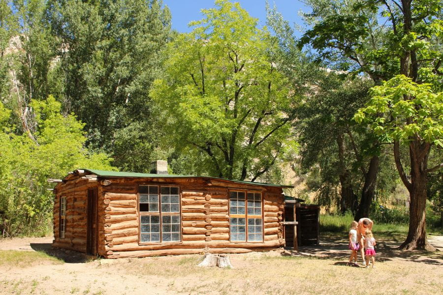 Mom with children standing in front of the historic Josie Morris Cabin at Dinosaur National Monument, Utah.