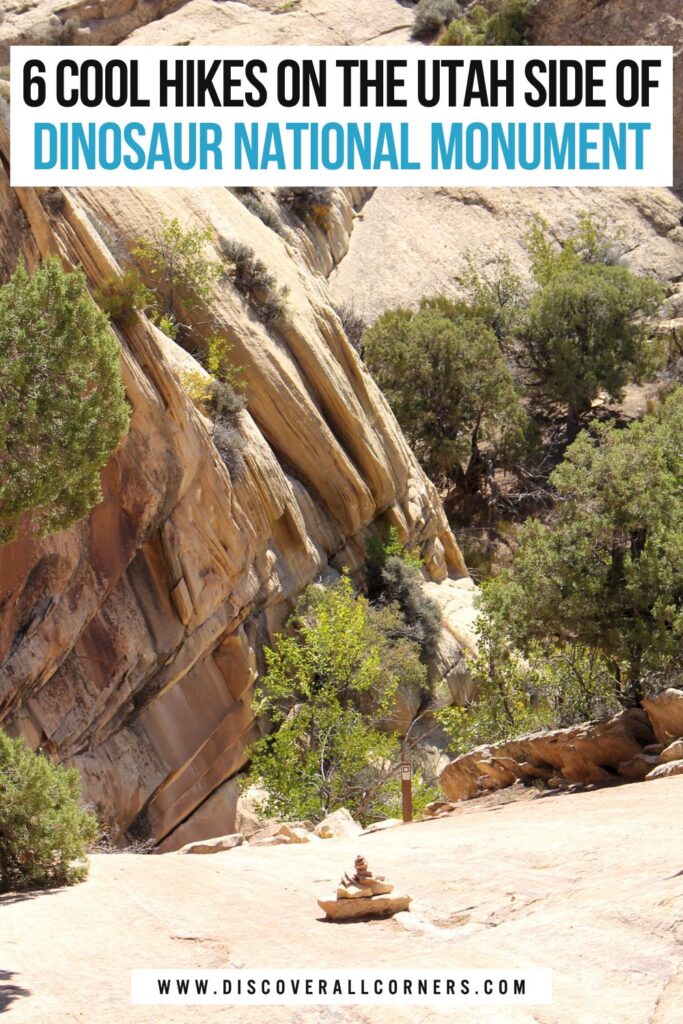 Hiking view in Dinosaur National Monument, Utah: slickrock trail section with a cairn and trail marker, surrounded by red rock formations and wide open desert scenery below.