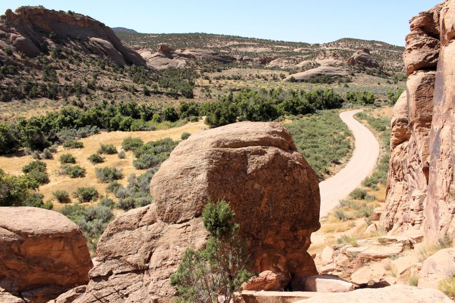 View from above of Cub Creek Road on the Tour of the Tilted Rocks, winding through a desert valley with colorful rock formations ahead.