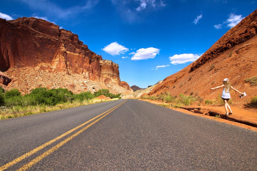 Child walking along a contrasting dark road through the colorful desert landscape near Capitol Reef National Park.
