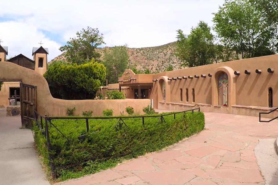 A walled courtyard of a chapel with decorative religious artwork and lush decorative pockets.