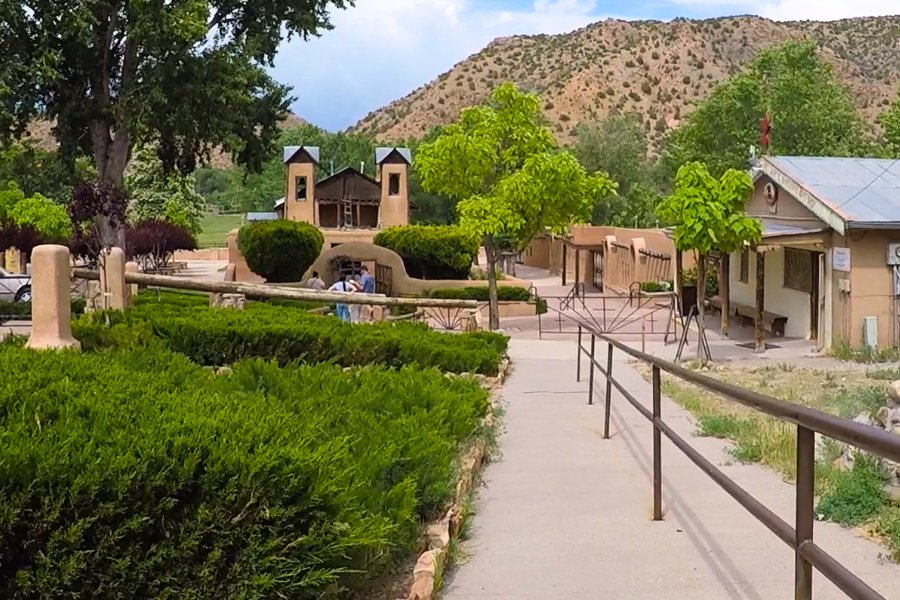 Adobe main chapel at El Santuario de Chimayó set within a peaceful, tree-filled courtyard.