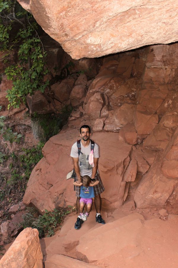 Family walking along a narrow steep rocky section of the Middle Emerald Pools connector trail, with stone steps and bordered by sandstone walls.