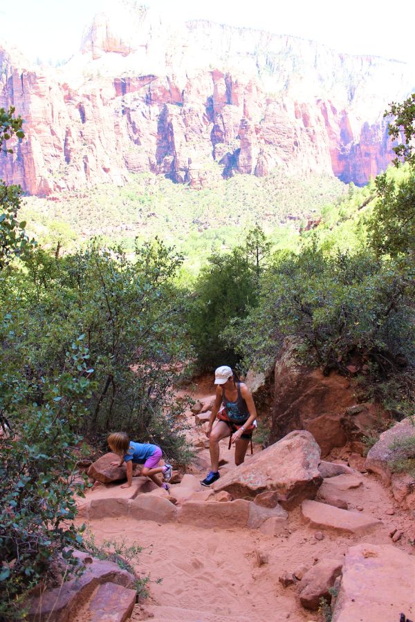 Family climbing on the rugged section of the Upper Emerald Pool Trail with larger rocks and uneven terrain.