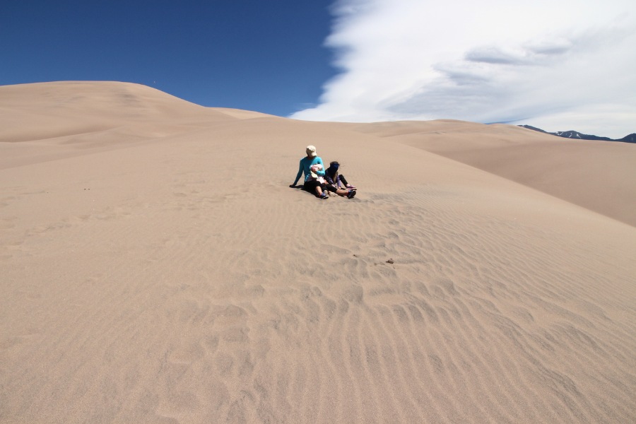Family resting on along a dune hike with more peaks up ahead.