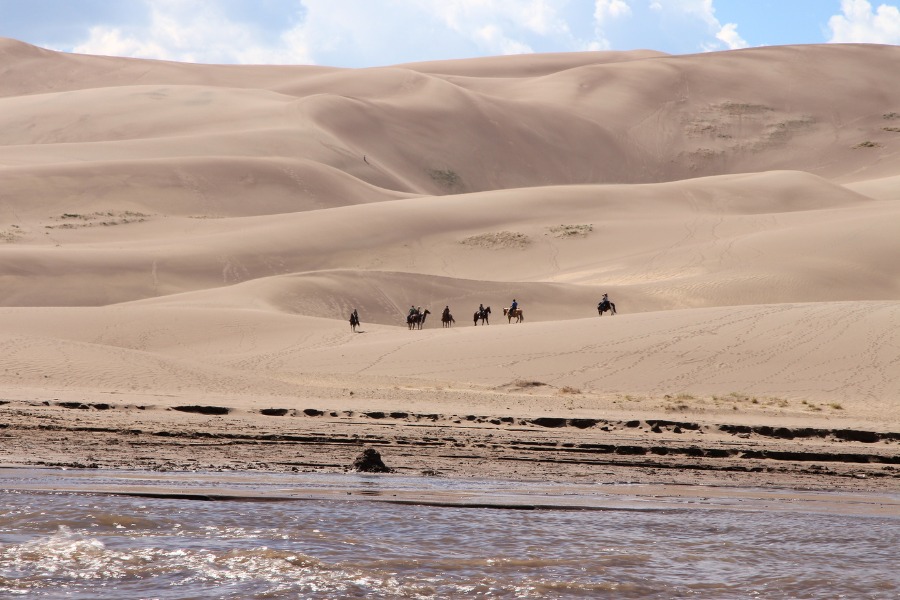 A group of horseback riders crossing the bottom section of the dunefield in Great Sand Dunes National Park.