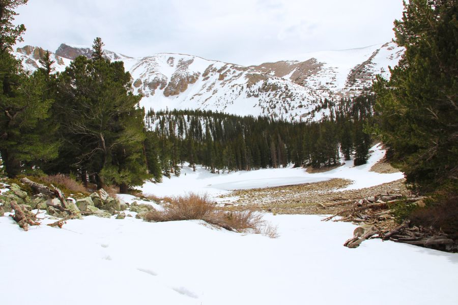 Frozen Lake Teresa surrounded by snow-covered terrain beneath Wheeler Peak in Great Basin National Park.