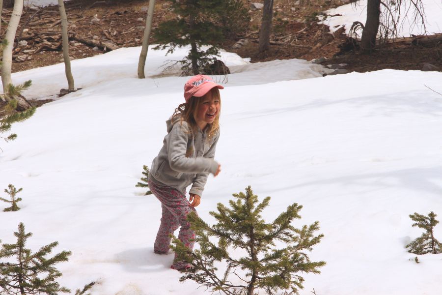 Child laughing while hiking through deep snow along the Lehman Creek Trail surrounded by forest.