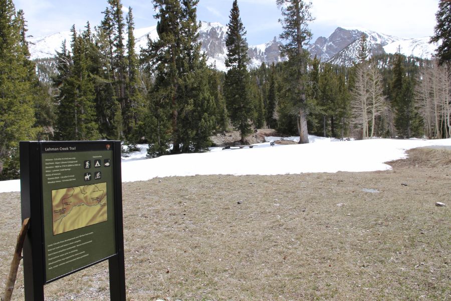 Upper Lehman Creek Trail trailhead sign near Wheeler Peak Campground with snow-covered mountains in the background.